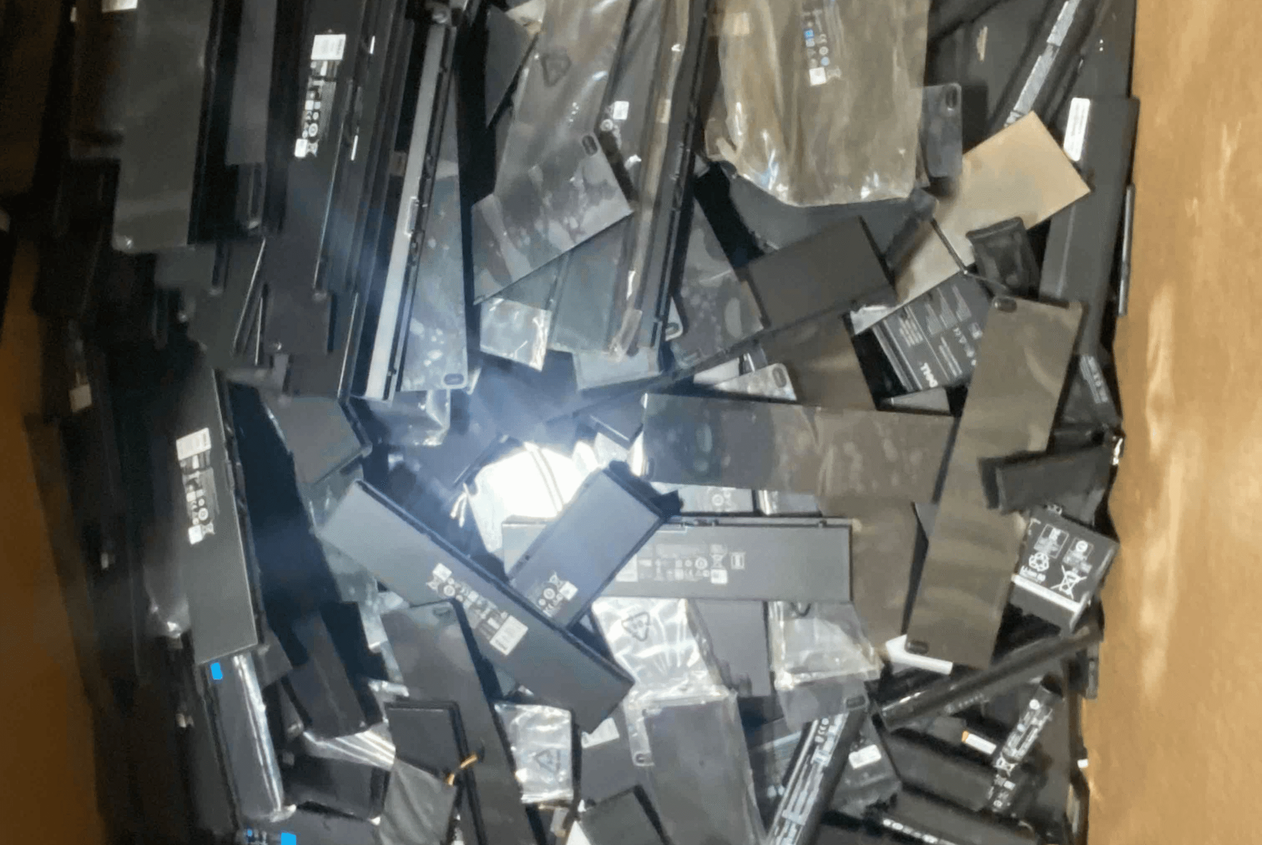 Lithium-ion polymer laptop batteries loosely piled inside of a Gaylord box for recycling